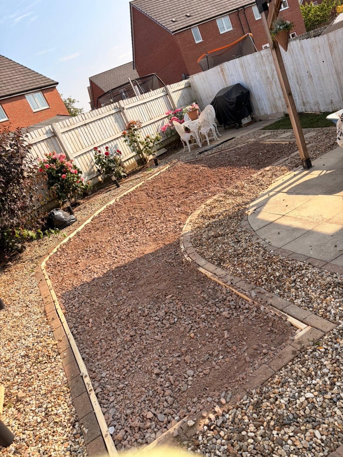 Lawn area excavated and filled with compacted crushed stone sub-base, with brick edging and timber formwork setting out the curved shape