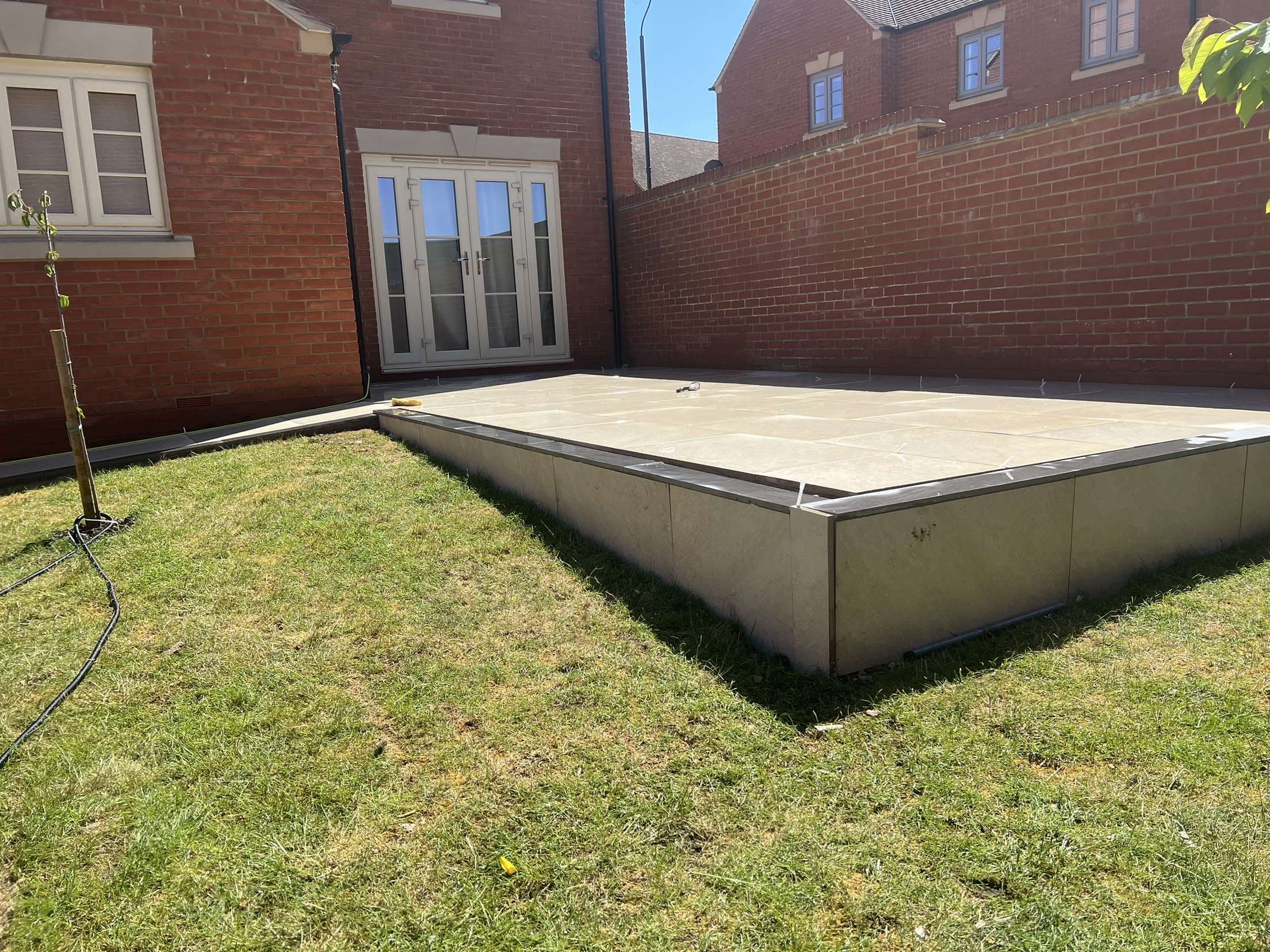 Raised porcelain patio with tiled edges surrounded by lawn