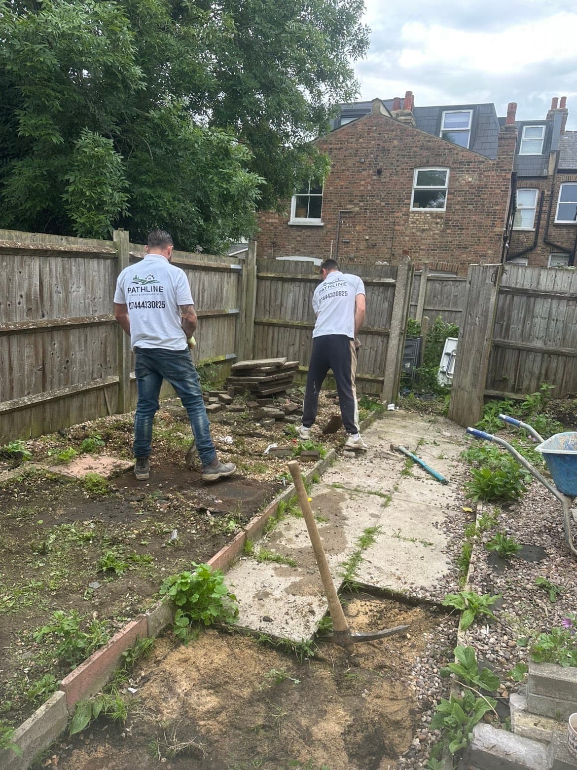 Pathline team in branded uniforms clearing an old overgrown garden and removing a cracked concrete path before installing a Kandla grey sandstone patio