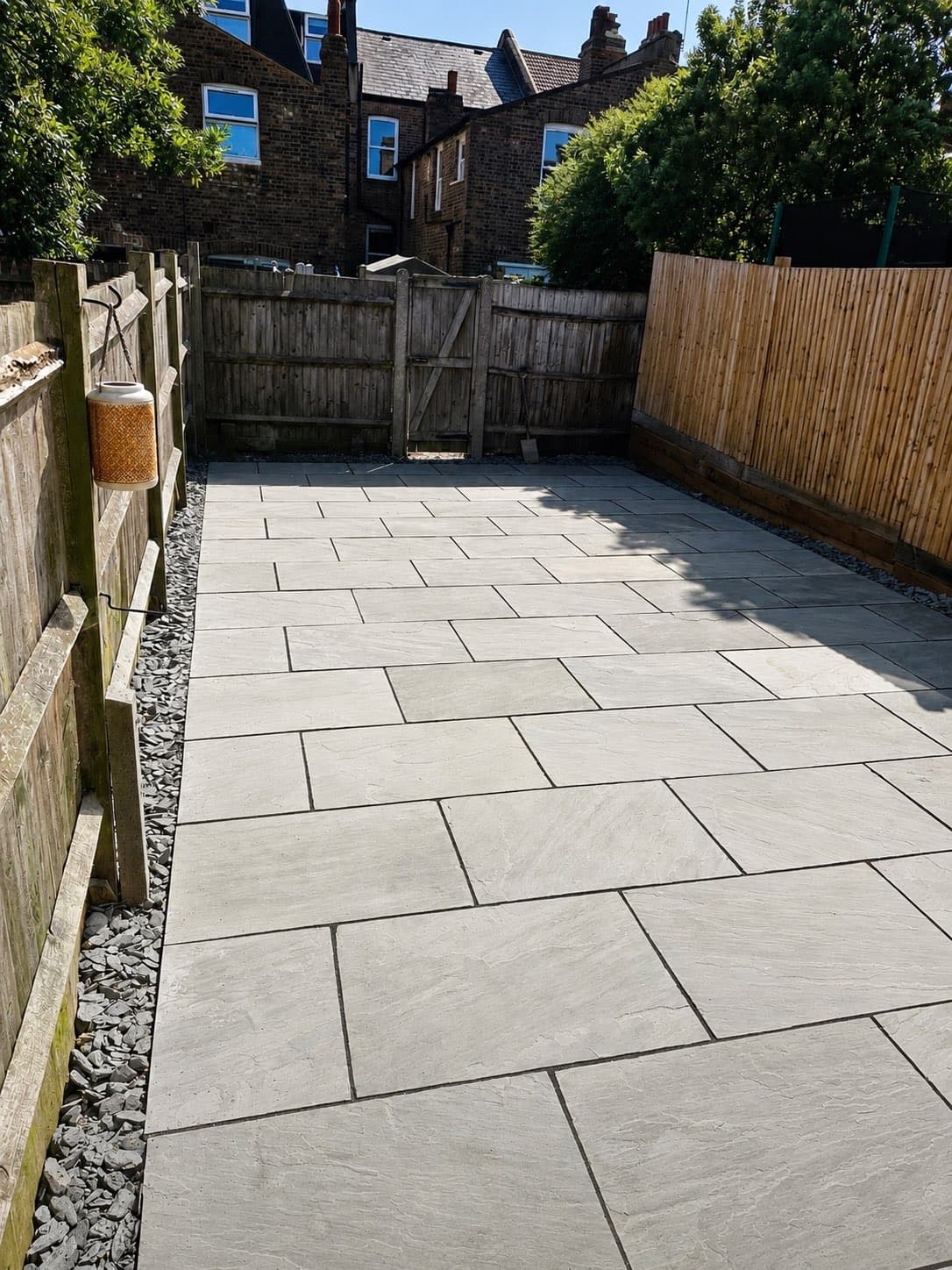 Completed Kandla grey Indian sandstone patio laid in a random pattern with slate gravel borders