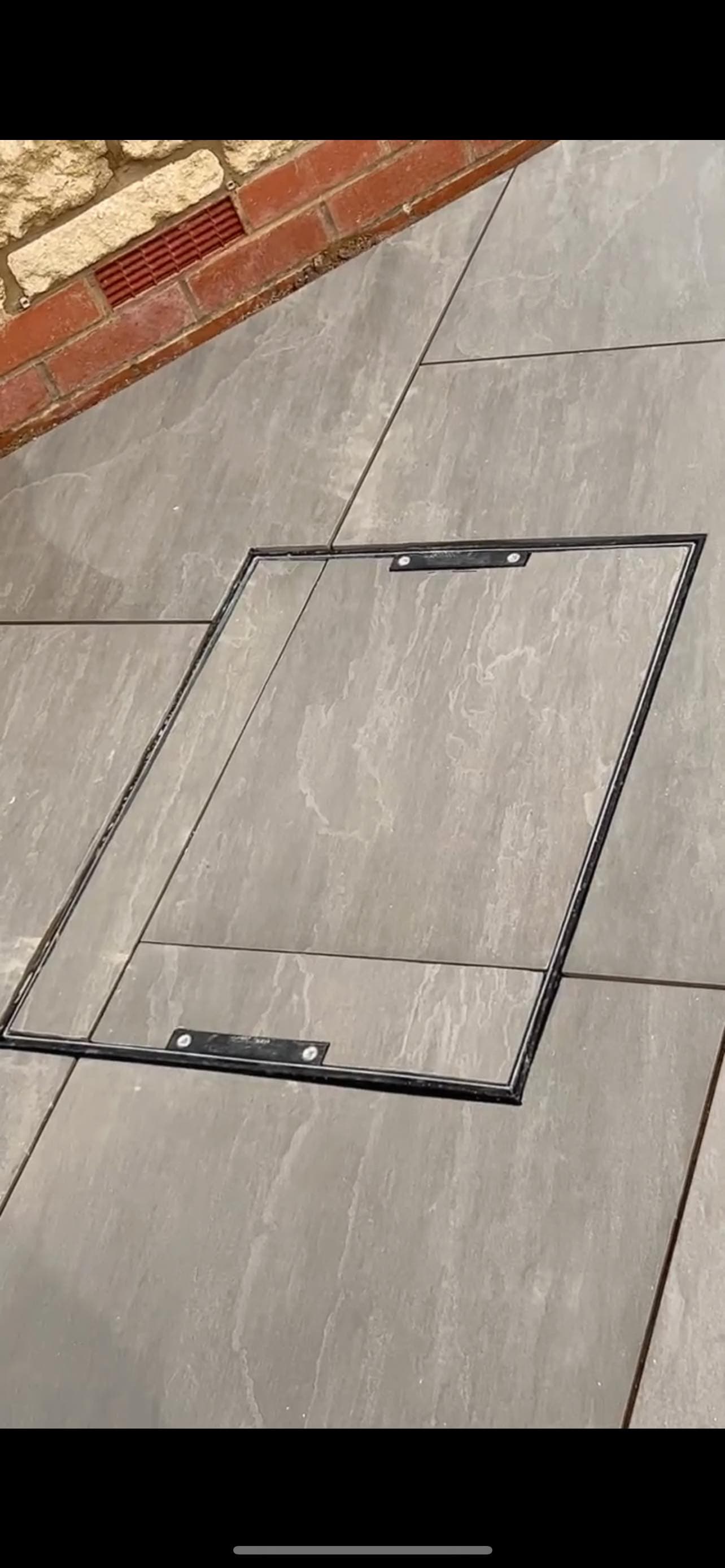 Recessed manhole cover tiled to match grey porcelain paving